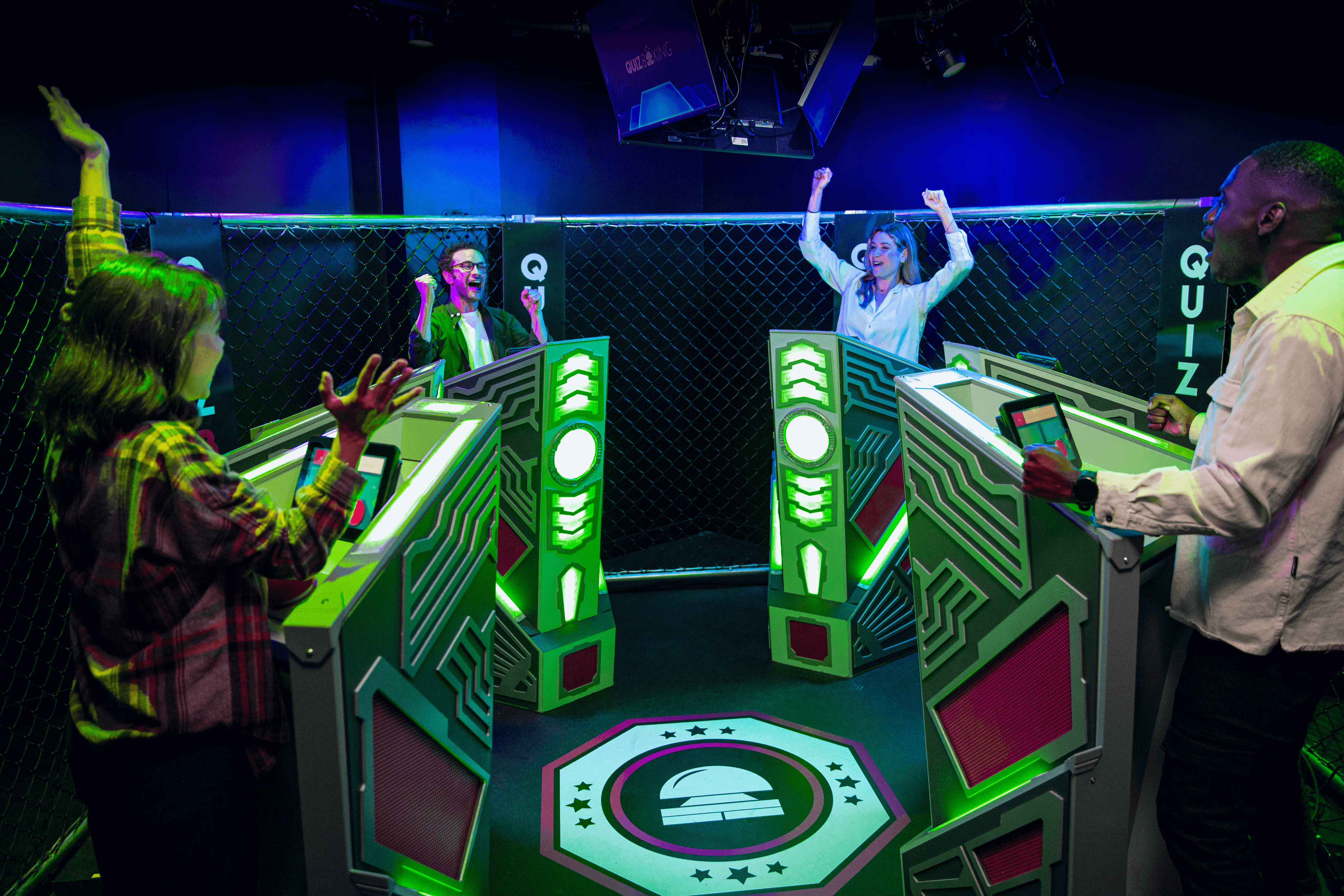 A group of 4 people inside the quiz arena at Quiz Boxing belfast. Each person is celebrating as they take part in the activity.